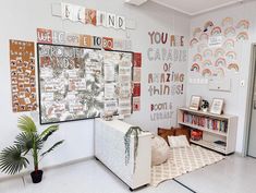 a room with posters on the wall and a couch in front of it, along with a potted plant