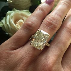 a woman's hand with a ring on it and a flower in the background