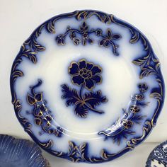 a blue and white plate sitting on top of a table next to a vase filled with flowers