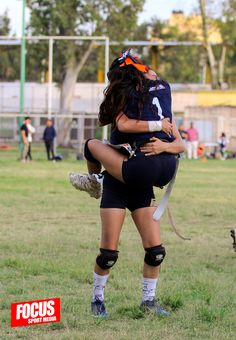 two women are hugging each other on the field