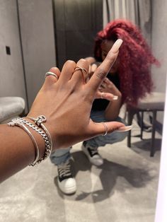 a woman with red hair is holding her hand up to the camera while she looks at her phone