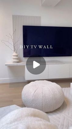 a living room with white furniture and a flat screen tv mounted on the wall above it