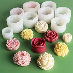 many different types of candles sitting on a table with one candle in the shape of roses