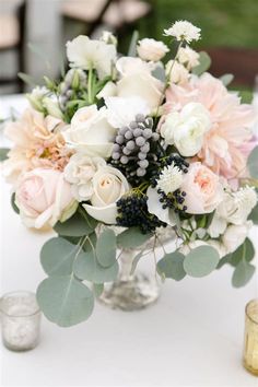 a vase filled with lots of flowers on top of a white tablecloth covered table