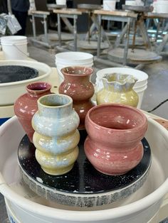 there are many vases sitting on top of each other in the bowl and they are all different colors