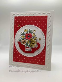 a red and white card with flowers on the front, and an ornate border around it