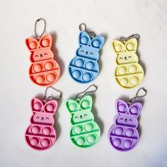 four keychains shaped like animals with sunglasses on them, all in different colors