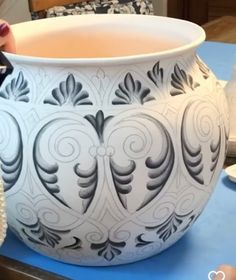 a large white vase sitting on top of a table next to a bowl filled with water