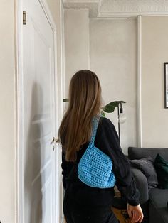 a woman with a blue crochet purse standing in a living room