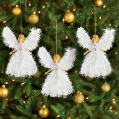 three white angel ornaments hanging from a christmas tree in front of a gold ornament