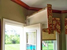 an open window with curtains hanging from it's sides and the outside view of a house in the background