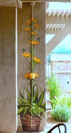 a potted plant sitting on top of a wooden table next to a wall with yellow flowers