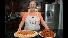 a woman in an orange shirt is holding two plates with spaghetti and meatballs on them