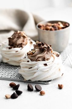 two cupcakes with chocolate frosting and nuts are on a silver serving tray