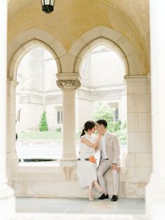 a bride and groom standing under an archway in the middle of a building with arches