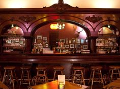 the inside of a bar with wooden tables and stools