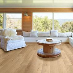 a living room with wood floors and white furniture on the floor, along with large windows