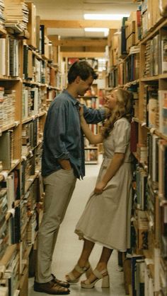 a man standing next to a woman in front of a book shelf filled with books