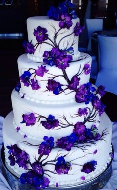 a white wedding cake with purple flowers on it