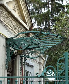 an ornate green metal structure on the side of a building