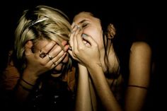 two women are covering their faces with their hands