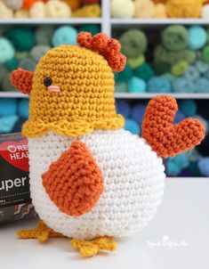 a crocheted chicken sitting on top of a table next to a can of beer