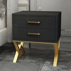 a black and gold side table with two drawers on one end next to a white couch