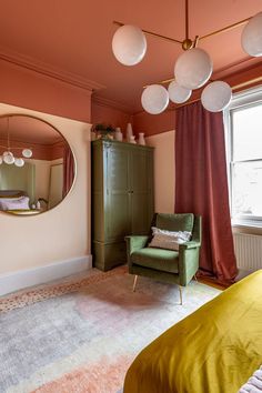 a green chair sitting in front of a mirror on top of a wooden dresser next to a window