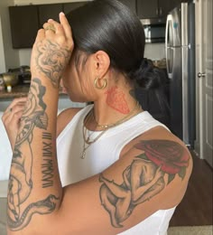 a woman with many tattoos on her arm and shoulder is looking at the camera while holding her hand up to her head