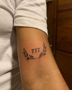 a person with a tattoo on their arm that reads 77th and has leaves around it