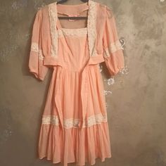 Vintage Darling Debs Tank Fit And Flare Midi Dress Beautiful Peachy Gauze Fabric With Lace Trim Fully Lined Zip Up Back Straps Unbutton To Be Cross Crossed Or Straight Matching Tie Front Bolero Ballon Sleeve Tie Front In Great Condition Please Reference Photos No Size Tags Fits Like An Xs Measures 47 Long 14 Across Chest 12 Across Waist Peach Square Neck Summer Dress, Pink Mini Length Vintage Dress For Summer, Pink Mini Vintage Dress For Summer, Spring Vintage Mini Dress With Lace Trim, Vintage Lace Trim Dress For Brunch, Orange Feminine Dresses For Daywear, Peach Lace Trim Dress For Summer, Orange Lace Trim Summer Dress, Orange Summer Dress With Lace Trim