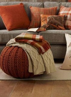 a living room filled with lots of pillows and blankets on top of a gray couch