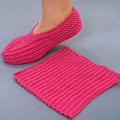 a woman's feet in pink knitted slippers on top of a gray surface