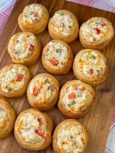 a wooden cutting board topped with mini muffins covered in cheese and toppings