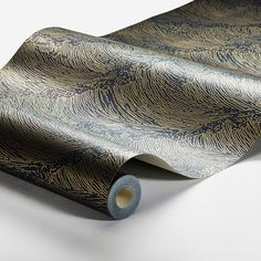 a roll of blue and gold wallpaper on a white surface