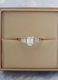 an engagement ring with three baguets in a box on top of a table