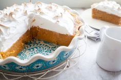 a pie sitting on top of a blue and white plate next to a cup of coffee