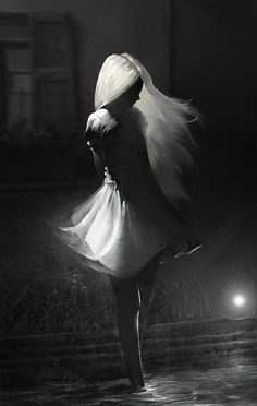 black and white photograph of a woman dancing in the rain with her hair blowing back