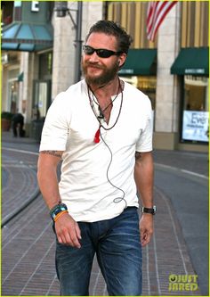 a man with sunglasses and a beard is standing on the street