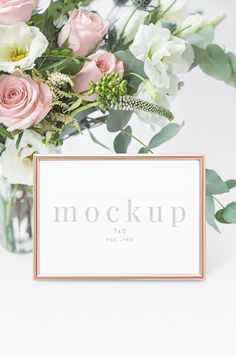 a vase filled with pink and white flowers next to a sign that says mock up