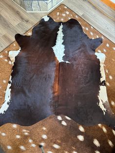 a brown and white cowhide rug with spots on it