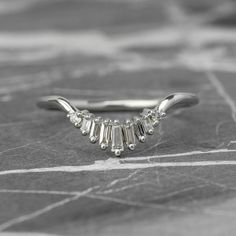 a white gold ring with five baguettes set in the middle, on a marble surface