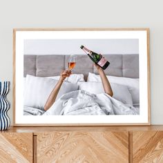 a woman laying in bed holding a bottle of champagne