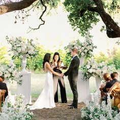 a bride and groom standing at the end of their wedding ceremony under an oak tree