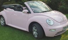 a pink convertible car parked in the grass