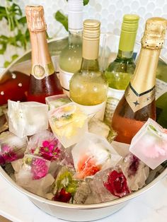 several bottles of wine and ice cubes in a bowl on a table with flowers