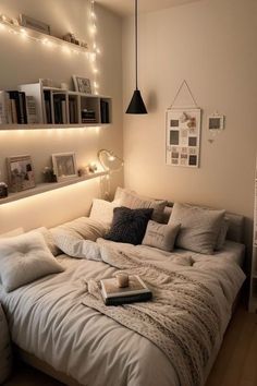 a white bed sitting in a bedroom next to a wall mounted bookshelf with lights on it