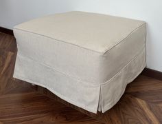 a white ottoman sitting on top of a hard wood floor