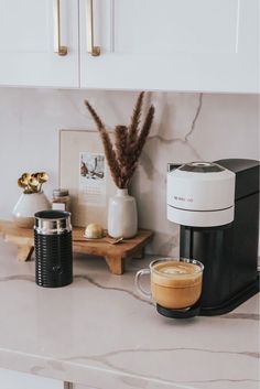 a coffee maker sitting on top of a kitchen counter next to a cup of coffee