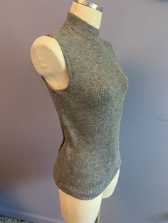 Vintage 1970's grey Acrylic stretch knit sleeveless turtleneck sweater made by Whistler's . Size Large, 40 1/2" bust, 25" length. Unworn deadstock in excellent condition with original tags! Grey Sleeveless Turtleneck Outfit, Fitted Sleeveless Gray Sweater Vest, Fitted Sleeveless Sweater Vest For Winter, Fitted Sleeveless Fall Sweater, Fitted Ribbed Sweater Vest For Winter, Gray Fitted High Neck Tops, Fitted Gray High Neck Tops, Fitted High Neck Gray Tops, Fitted Turtleneck Sweater Vest For Fall